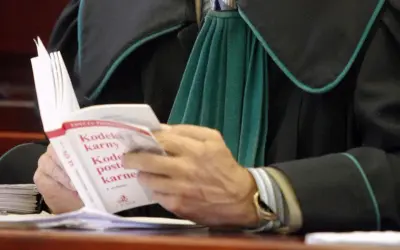 Prawnik w todze czyta Kodeks karny.