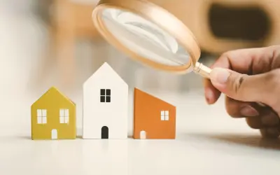 Lente d'ingrandimento esamina tre casette di legno, evidenziando la differenza tra cessione e subentro nel mercato immobiliare.