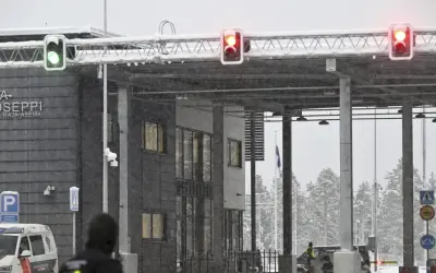 Grön trafiksignal vid gränsövergången Joensuu, Finland. Snö faller över byggnaden och träden. En polisbil syns. Gränsen mellan Ryssland och Finland är stängd.