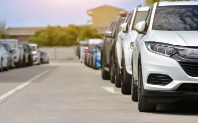 Rząd białych i ciemnych samochodów na parkingu. Może to być scena z transakcji, gdzie nastąpiło zaniżenie wartości samochodu na umowie.