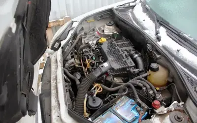 Silnik Renault Kangoo 1.5 dCi, widok komory silnika z otwartą maską. Widać akumulator, filtry i przewody.