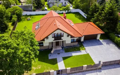 Piękny dom z czerwonym dachem i ogrodem. Zastanawiasz się, ile kosztuje projekt domu?