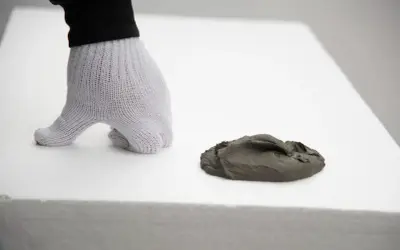 Ręka w rękawicy przygotowuje masę do wylewki na styropianie. Kluczowe jest, ile styropianu pod wylewkę zostanie użyte.