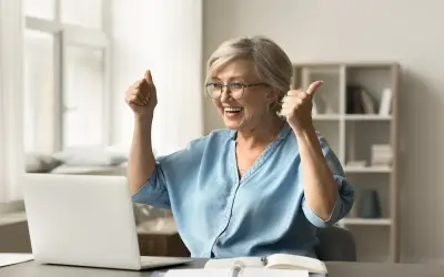 Szczęśliwa kobieta z kciukami w górze, cieszy się z pomyślnej odprawy emerytalnej online.