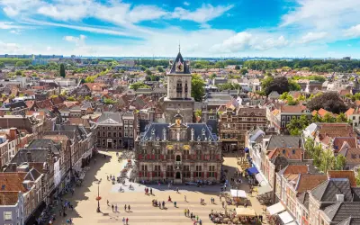 Luftaufnahme von Delft mit dem Rathaus im Zentrum. Entdecken Sie die charmanten Gassen und versteckten Plätze – echte Delft Geheimtipps.