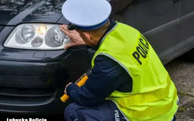 Policjant sprawdza reflektor, czy żarówki postojowe led są legalne. Lubuska Policja.