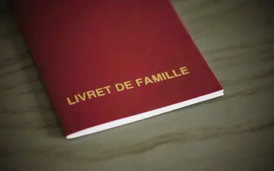 Livre rouge "LIVRET DE FAMILLE" avec mention marginale, document officiel de famille.
