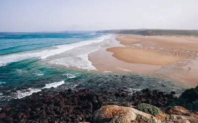Piękne plaże i turkusowe morze, idealne na algarve wakacje. Surferzy łapią fale, a skały tworzą malowniczy brzeg.