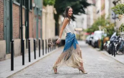 Mujer con falda larga de flecos y top blanco, lista para la feria de abril sin vestido.