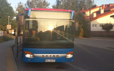 Niebieski autobus Setra z Giżycka do Olsztyna, sprawdzam express bus Giżycko Olsztyn cena. Słońce odbija się w szybie.