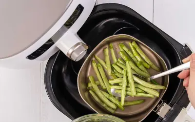 Gröna bönor läggs i en korg för en varm luft ugn.