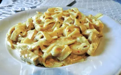 Pyszne makaron tagliatelle z kurczakiem w kremowym sosie, podane na białym talerzu.