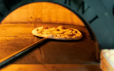 Pizza na łopacie w piecu, gdzie powstała pizza. Ciepło i tradycja wypieku.