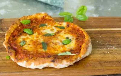 En perfekt pizza i airfryer, med smält ost och färsk basilika, serverad på en träskärbräda.
