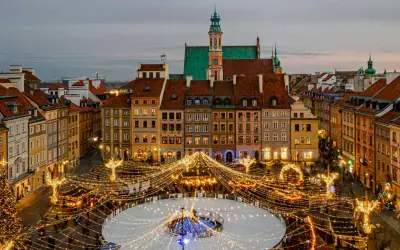 Magiczny zimowy wieczór w Warszawie. Rynek Starego Miasta rozświetlony tysiącami lampek, lodowisko i choinka tworzą idealną atmosferę na city break w Polsce.