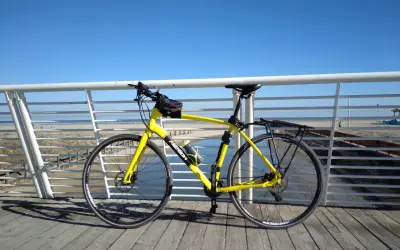 Bicicletta gialla pronta per un giro a Rimini Cattolica, con il mare e la spiaggia sullo sfondo.