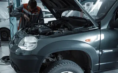 Mechanik wymienia żarówkę w przednim reflektorze Skody Fabii 3.