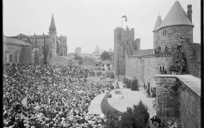 Vue d'un spectacle dans les arènes de Carcassonne, avec une foule nombreuse assise et la cité médiévale en arrière-plan.