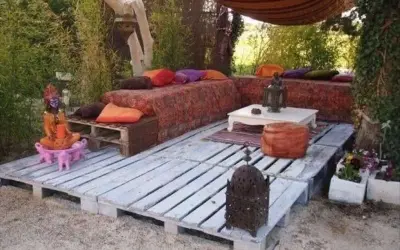 Un rincón zen con sofás y mesas bajas creados con jardineras con palets, cojines coloridos y faroles.
