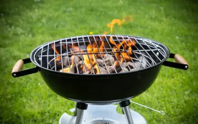 Rozpalony grill węglowy z płomieniami na trawie. Idealny do nauki, jak rozpalic grilla na letnie wieczory.