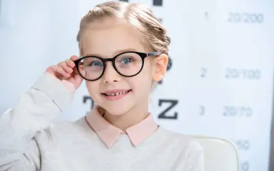 Uśmiechnięta dziewczynka z okularami, u której wykryto bardzo dużą wadę wzroku u dziecka.
