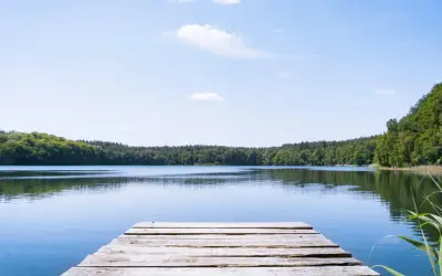 Holzsteg am ruhigen See, umgeben von grünen Wäldern. Ein perfekter Ort für einen geheimtipp mecklenburgische seenplatte Urlaub.