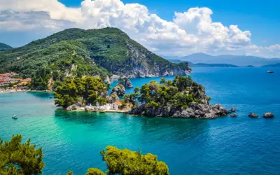 Malownicze **Lefkada loty z Polski** to marzenie o rajskich wakacjach. Widok na turkusowe morze, zielone wzgórza i urokliwą zatoczkę z białą kapliczką.