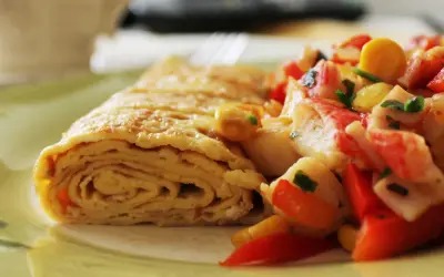 Zrolowany omlet po japońsku z kolorową sałatką z warzyw i surimi.