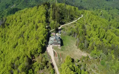 Widok z lotu ptaka na schronisko i szlak na stożek z Wisły Głębce, otoczone bujną, zieloną roślinnością.