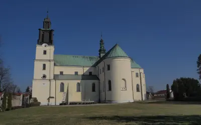 Bazylika w Gidlach z charakterystyczną wieżą i zielonym dachem, na tle błękitnego nieba.
