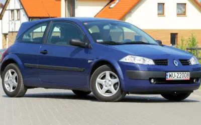 Niebieski Renault Megane 2, widok z przodu. Widać reflektory, atrapę chłodnicy i tablicę rejestracyjną.