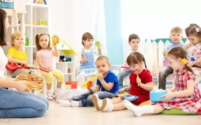 Dzieci na zajęciach muzycznych, grają na instrumentach. Ciekawe, ile zarabia przedszkolanka za taką pracę.
