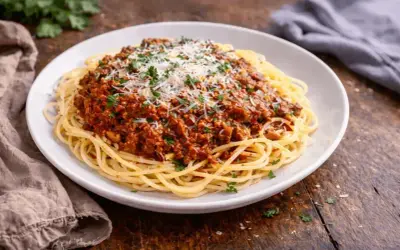 Pyszne spaghetti bolognese, idealne na prosty obiad. Makaron z bogatym sosem mięsnym, posypany parmezanem i natką pietruszki.