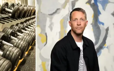 En man med en blick som antyder "looksmaxxing meaning" står framför en abstrakt tavla. Till vänster syns en hylla med hantlar.