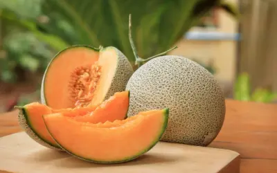Melón entero y cortado, mostrando su pulpa naranja y semillas. Un festín de las propiedades del melón.