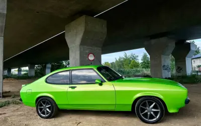 Zielony Ford Capri z lat 70. pod betonowym wiaduktem.