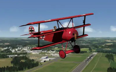 Ein rotes Fokker-Flugzeug mit Eisernem Kreuz fliegt über eine grüne Landschaft mit einer Stadt und einem Flugfeld.