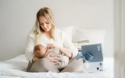 En mamma ammar sitt lilla barn. Bredvid dem står en bröstpump och dess förpackning.