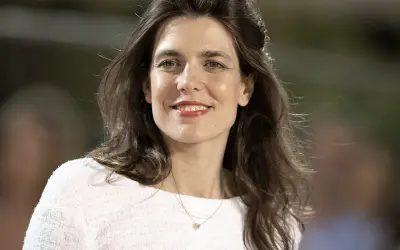 Charlotte Casiraghi sonríe con un collar delicado y un suéter blanco.