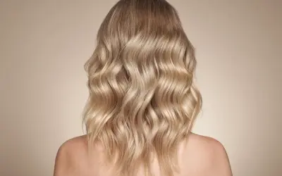 Piękne, falowane beżowe blond włosy opadające na ramiona.