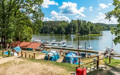 Namioty rozbite nad jeziorem, gdzie cumują żaglówki. Idealne miejsce na wypoczynek, prawdziwy pole namiotowe Mazury.