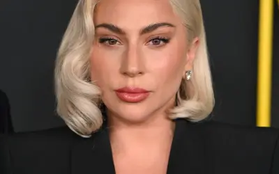 Lady Gaga, z blond włosami i makijażem, w czarnej marynarce. Czy Lady Gaga ma dziecko? To pytanie nurtuje fanów.