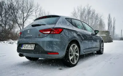 Szary Seat Leon FR w zimowej scenerii, pokryty śniegiem.