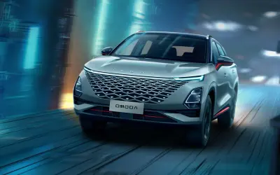 Nowoczesny SUV OMODA pędzi nocą przez futurystyczne miasto. Omoda co to za marka? To styl i innowacja.