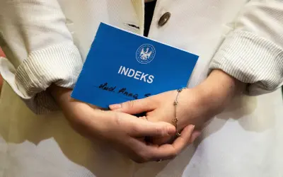 Kobieta trzyma indeks, zastanawiając się, czy studia liczą się do emerytury.