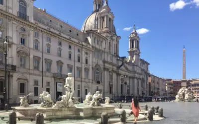 Una donna passeggia nella splendida Piazza Navona, ammirando la Fontana dei Quattro Fiumi e la maestosa chiesa.