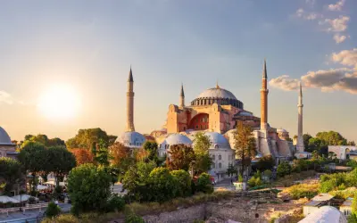 Majestatyczny meczet Hagia Sophia w Stambule, z minaretami i kopułami, oświetlony zachodzącym słońcem.