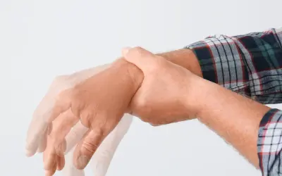Drżąca ręka mężczyzny w kratę, symbolizująca zespół abstynencyjny. Leki mogą pomóc złagodzić objawy.