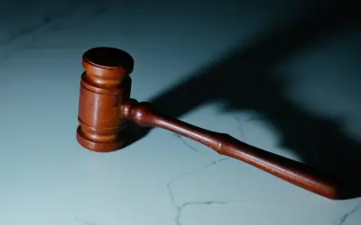 Drewniany młotek sędziowski na marmurowym blacie. Symbolizuje sprawiedliwość i prawa pracownika, w tym 5 praw pracownika.