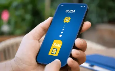 Dłoń trzyma smartfon z ekranem pokazującym ikonę karty SIM i symbol chipa, symbolizujące kartę eSIM.